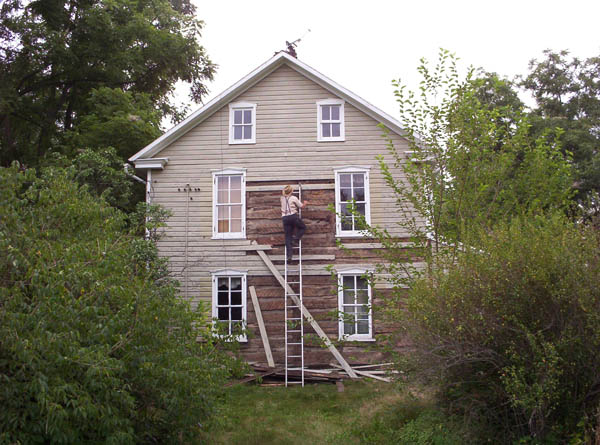 Huge log house hidden under old siding.